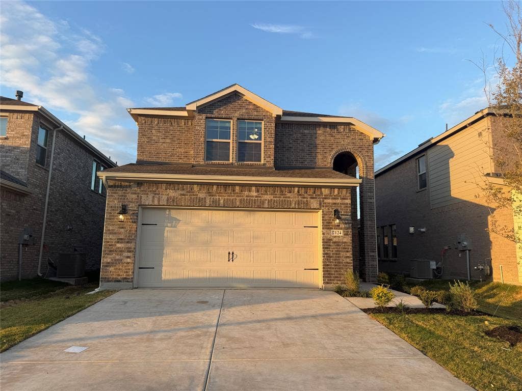 Two-story brick exterior featuring a multi-gabled roofline, concrete driveway, and attached two-car garage