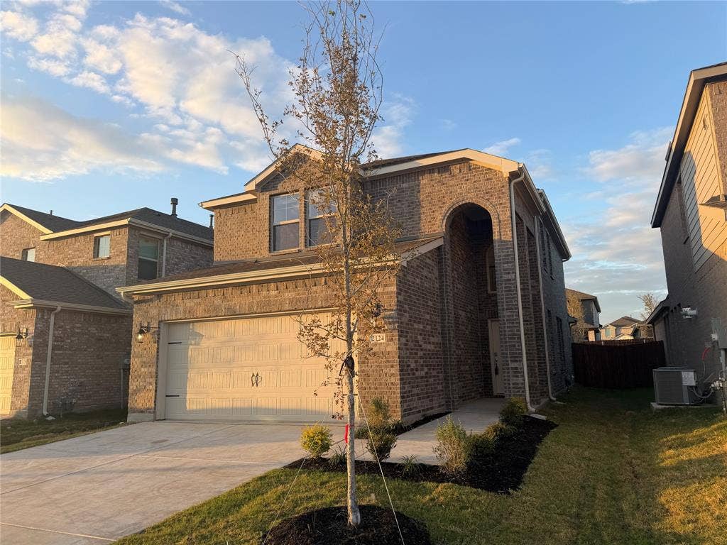 Two-story brick exterior featuring an arched entryway, two-car garage, and concrete driveway
