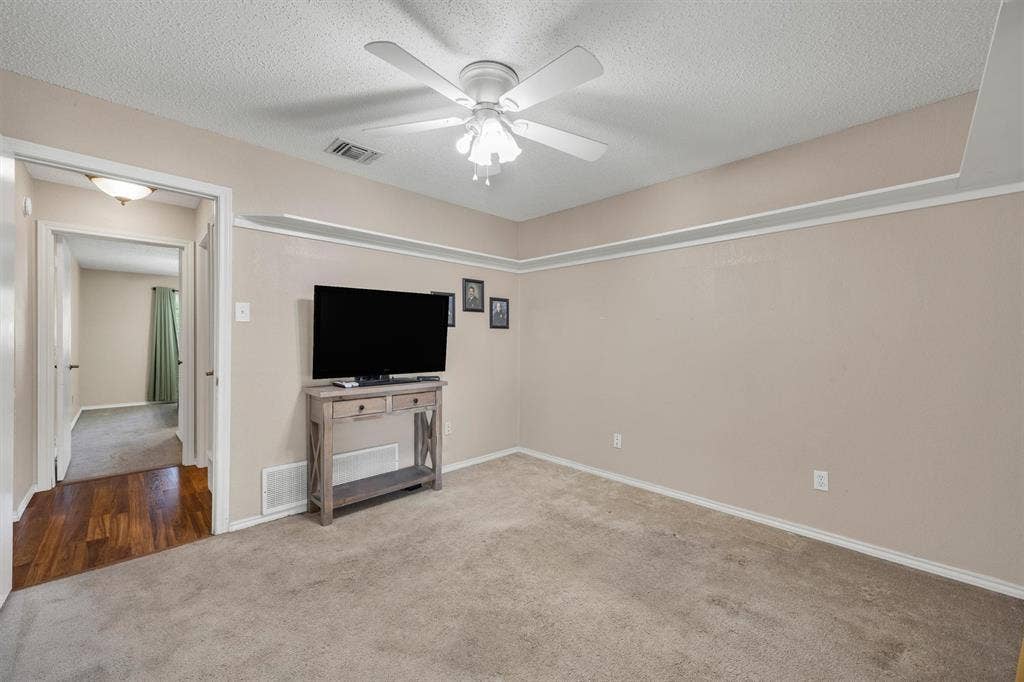 1025 Brownfield Drive, Mesquite, TX 75150 Neutral-toned interior featuring wall-mounted crown molding, ceiling-mounted light fixture with a fan, carpeting, and wood-finish flooring