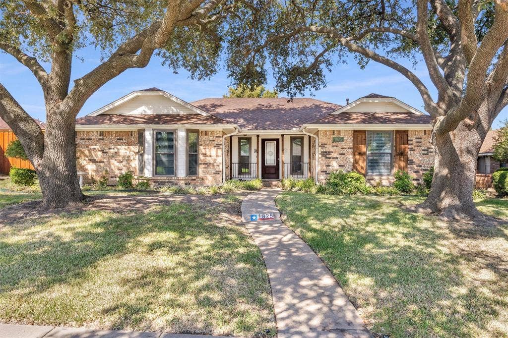 1025 Brownfield Drive, Mesquite, TX 75150 Single-story brick exterior featuring a multi-gabled roofline, front-facing bay windows, wood-shutter accents, and mature shade trees