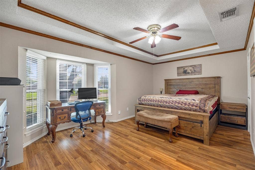 1025 Brownfield Drive, Mesquite, TX 75150 Tray ceiling with decorative wood trim, bay window, and wood-finish flooring