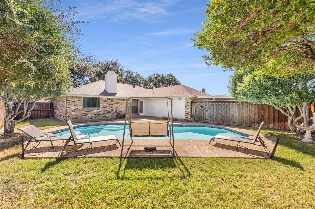 1025 Brownfield Drive, Mesquite, TX 75150 Private backyard featuring an in-ground swimming pool, concrete decking, mature trees, and wood perimeter fencing