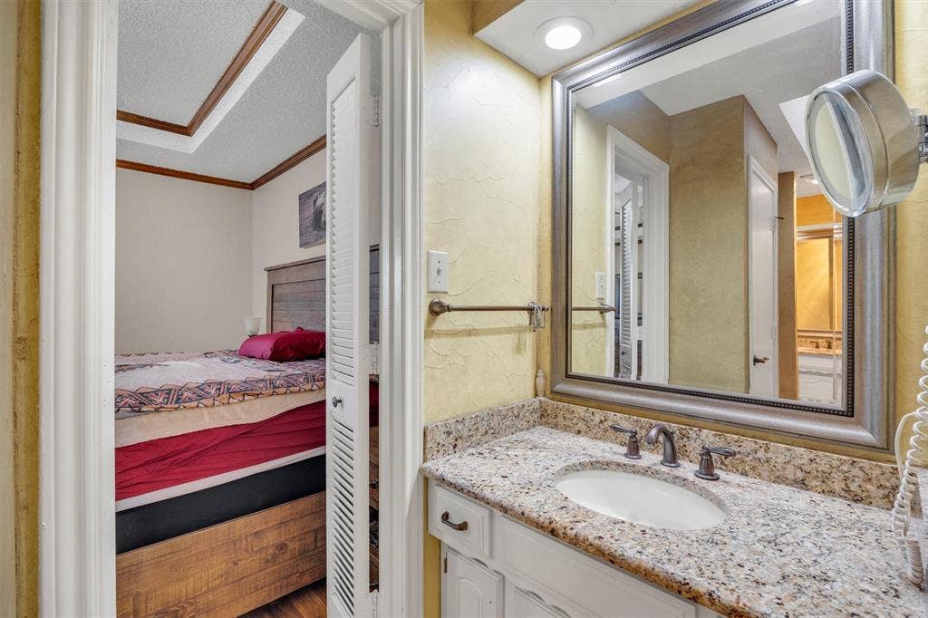 1025 Brownfield Drive, Mesquite, TX 75150 Bathroom vanity featuring a stone-composite countertop, undermount sink, multi-handle faucet, framed wall mirror, and white cabinetry