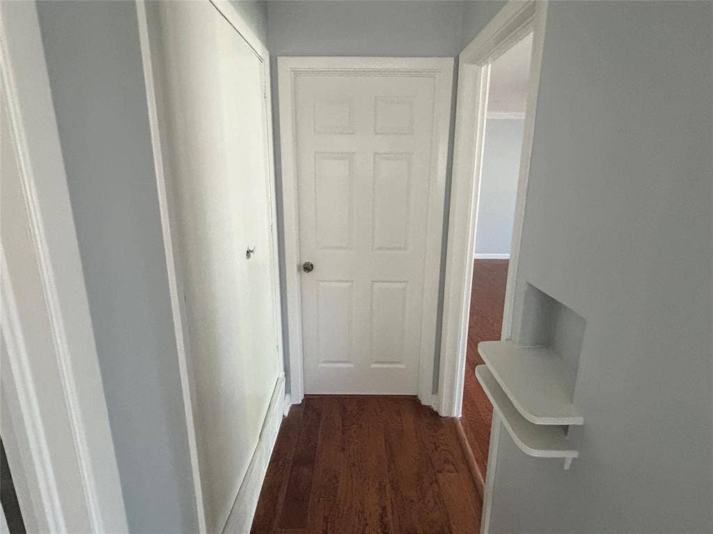 3136 Chatsworth Drive, Farmers Branch, TX 75234 Hallway featuring wood-finish flooring, a six-panel door, floor-to-ceiling closet cabinetry, and a built-in recessed wall niche with dual shelving