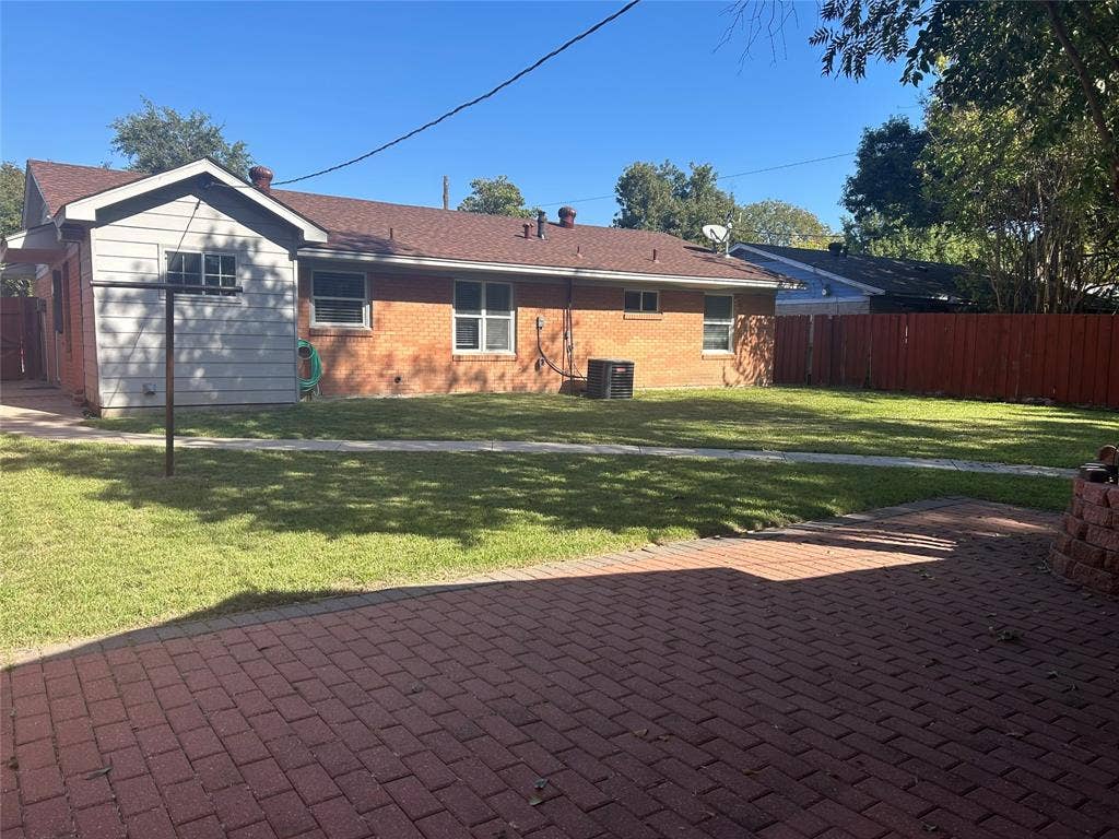 3136 Chatsworth Drive, Farmers Branch, TX 75234 Backyard featuring a red brick paver patio, a grassy lawn, and red privacy fencing