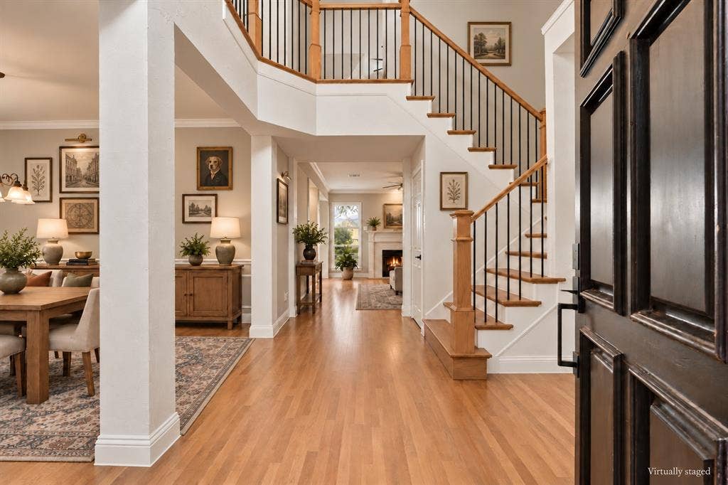 511 Clover Leaf Lane, McKinney, TX 75072 Foyer featuring wood-finish flooring, a staircase with a wooden handrail and metal balusters, and a fireplace with a decorative mantel