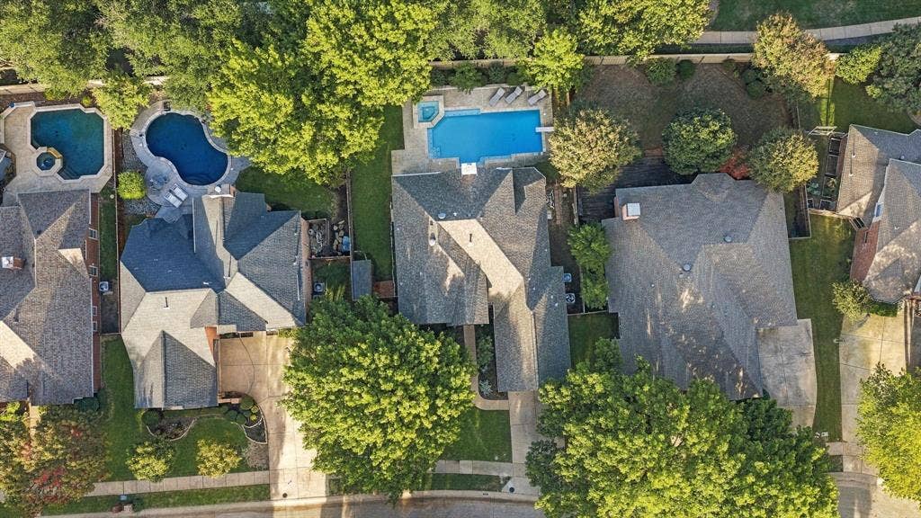 511 Clover Leaf Lane, McKinney, TX 75072 Aerial perspective showcasing a residential property featuring an in-ground swimming pool, an integrated spa, paved hardscaping, and mature trees on a landscaped lot