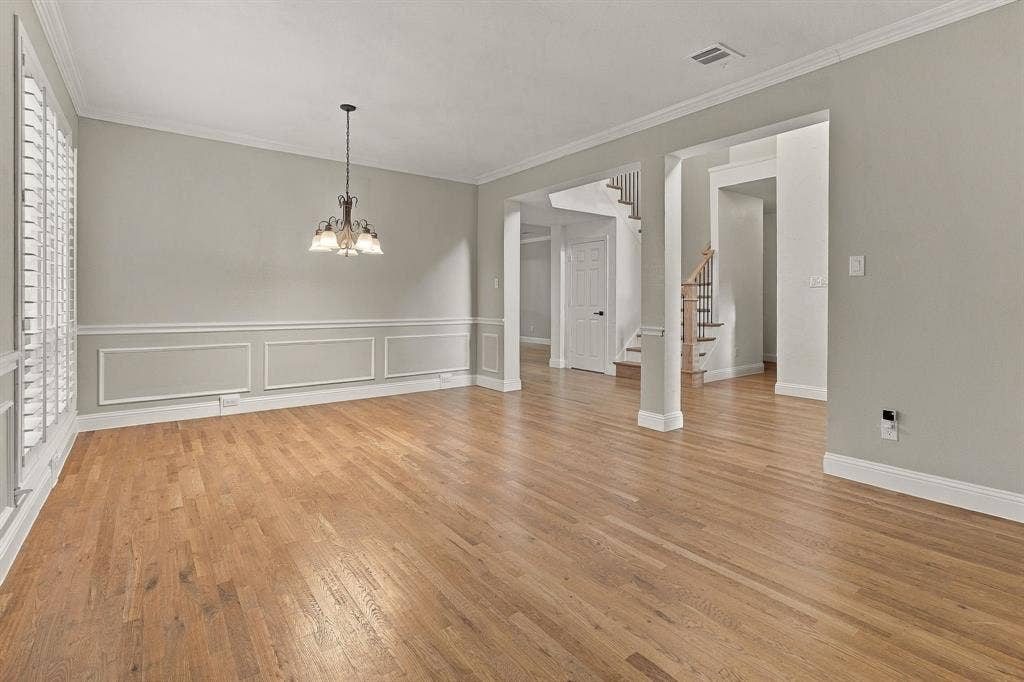511 Clover Leaf Lane, McKinney, TX 75072 Interior room featuring wood-finish flooring, wainscoting, multi-pane window shutters, and a multi-arm chandelier