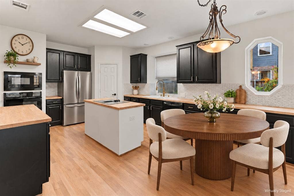 511 Clover Leaf Lane, McKinney, TX 75072 Kitchen featuring black cabinetry, wood-finish countertops, an island with a built-in cooktop, a mosaic tile backsplash, and recessed skylights