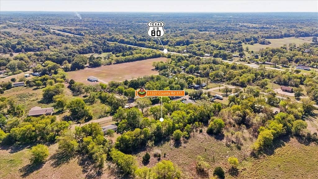 Aerial view of expansive acreage featuring mature trees, open pastureland, and established perimeter vegetation