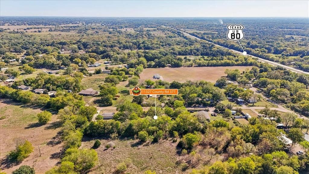 Aerial perspective of expansive acreage featuring mature tree clusters, open pasture land, and defined property boundaries