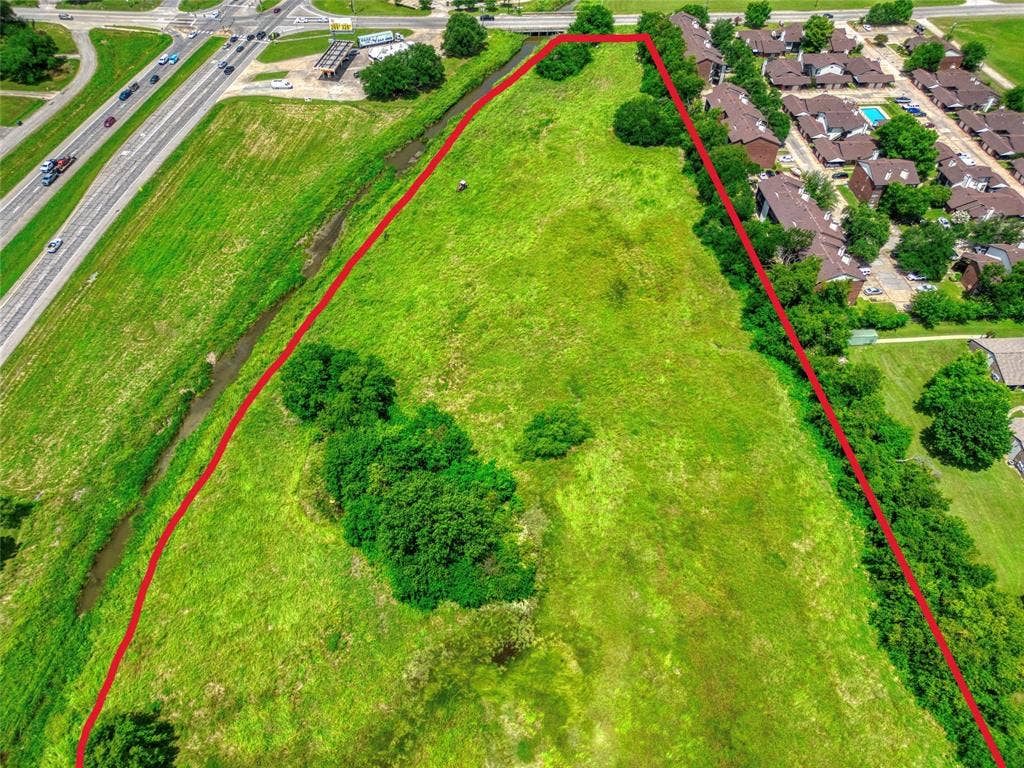 0000 King Street, Greenville, TX 75401 Expansive undeveloped parcel featuring open grassy terrain, clusters of mature trees, and a bordering natural drainage way