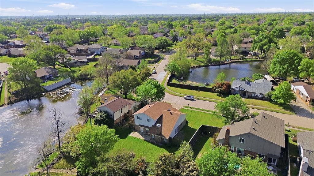 5514 Round Rock Road, Garland, TX 75044 Aerial perspective of a suburban neighborhood featuring a residential lot with direct water frontage, a spacious backyard, and mature trees