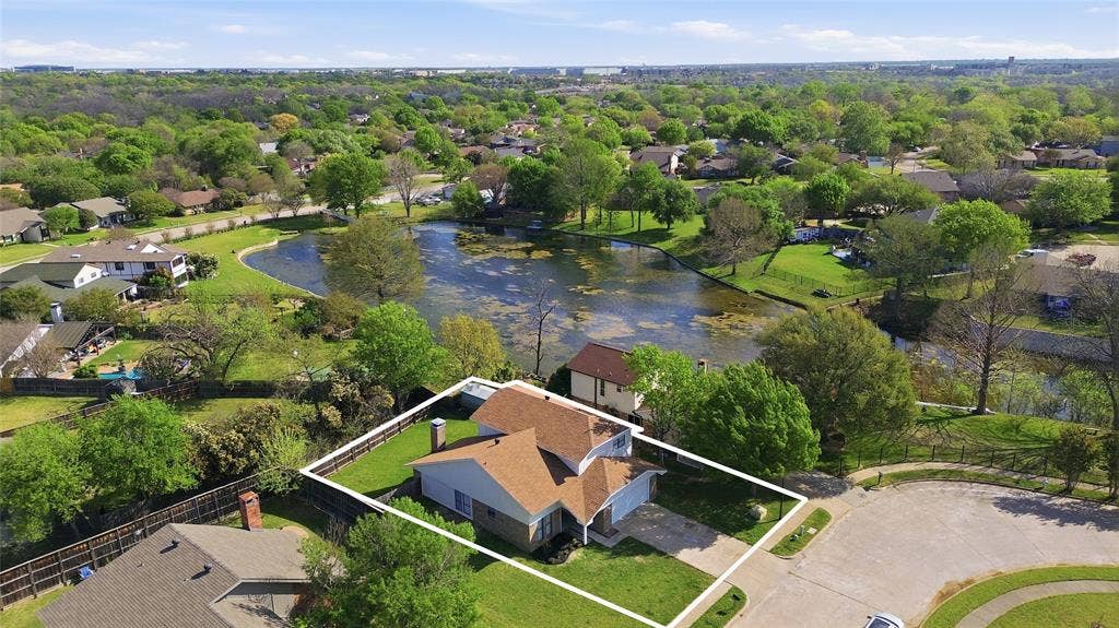 5514 Round Rock Road, Garland, TX 75044 Aerial perspective of a multi-level residence featuring a brick and siding exterior, a composition shingle roof, an attached garage, and a fenced backyard