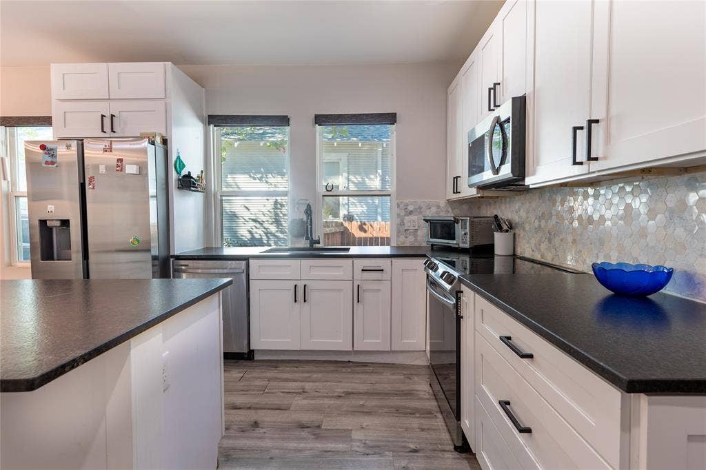 608 N Edgefield Avenue, Dallas, TX 75208 Updated center-island kitchen with an eat-in bar, new cabinetry, stainless-steel appliances, new fixtures, a large farmhouse sink, and lots of natural light.
