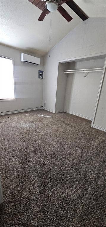 Vaulted ceiling with a ceiling fan, wall-mounted climate control unit, closet with integrated shelving, and neutral wall-to-wall carpeting