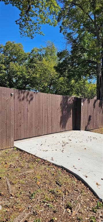 Solid wood privacy fencing featuring a reinforced sliding gate and concrete driveway surface