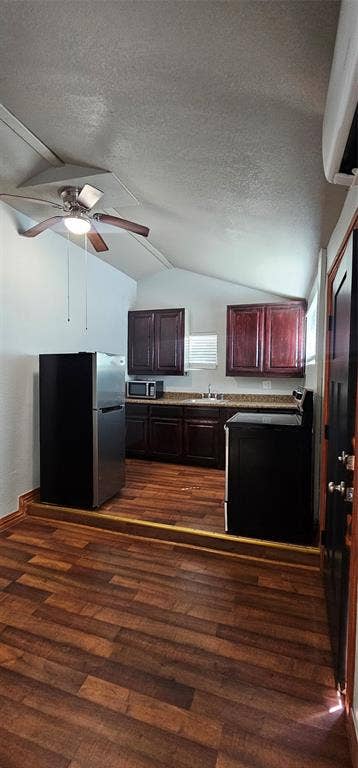 Kitchen featuring dark wood cabinetry, stone-finish countertops, stainless steel refrigerator, wood-finish flooring, and a ceiling fan