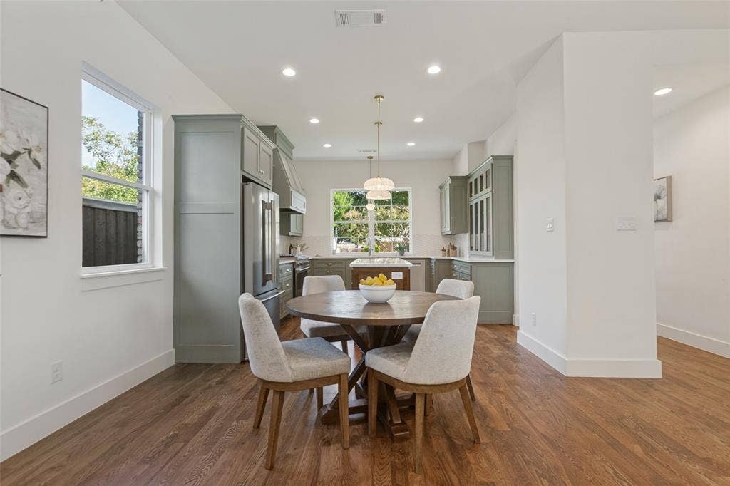 304 S Weatherred Drive, Richardson, TX 75080 Kitchen featuring sage-toned cabinetry, an island with countertop seating, stainless steel appliances, recessed ceiling lighting, and wood-finish flooring