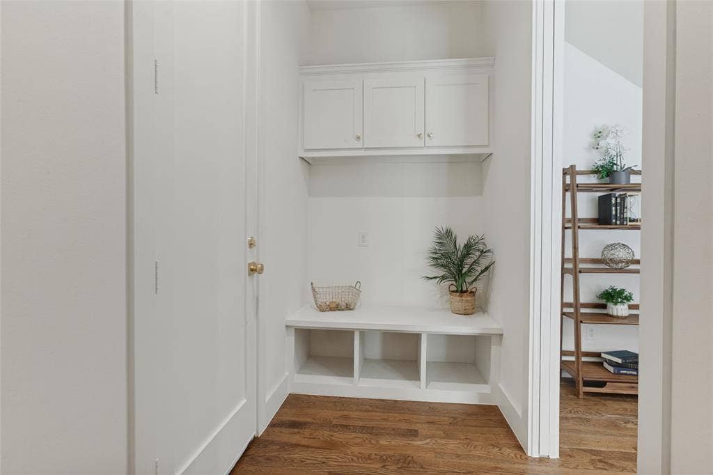 304 S Weatherred Drive, Richardson, TX 75080 Built-in white cabinetry featuring upper storage units and lower open cubbies with a bench seat, complemented by wood-finish flooring