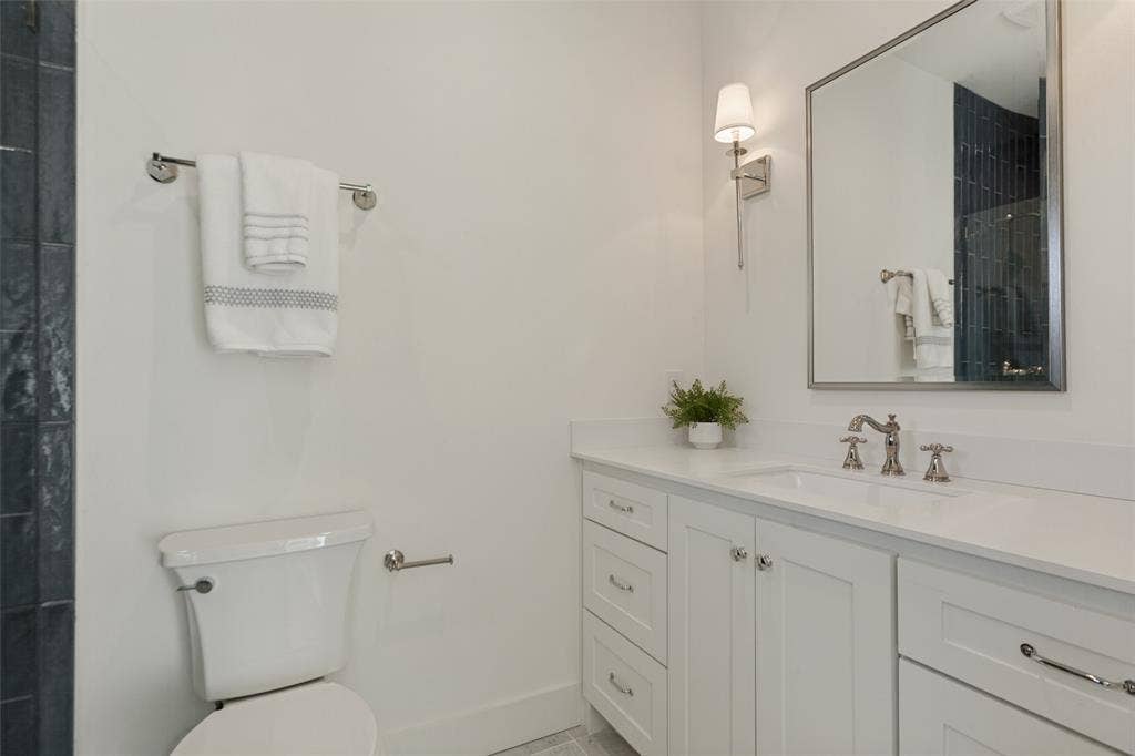 304 S Weatherred Drive, Richardson, TX 75080 White shaker-style cabinetry vanity with a solid surface countertop, undermount sink, wall-mounted polished nickel faucet, and rectangular framed mirror