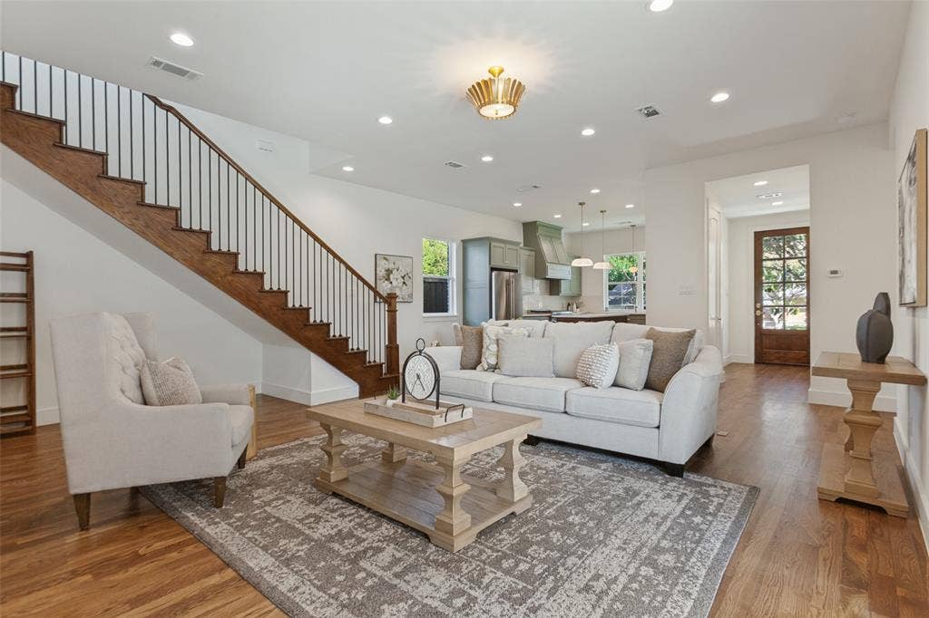 304 S Weatherred Drive, Richardson, TX 75080 Open-concept living space featuring wood-finish flooring, recessed lighting, and a staircase with a wood handrail and metal balusters