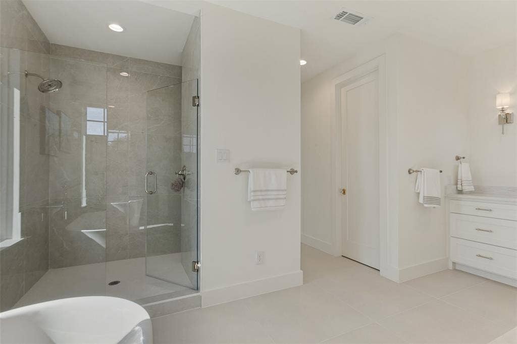 304 S Weatherred Drive, Richardson, TX 75080 Walk-in shower with floor-to-ceiling tile, frameless glass enclosure, wall-mounted shower head, white vanity with stone countertop, and recessed lighting