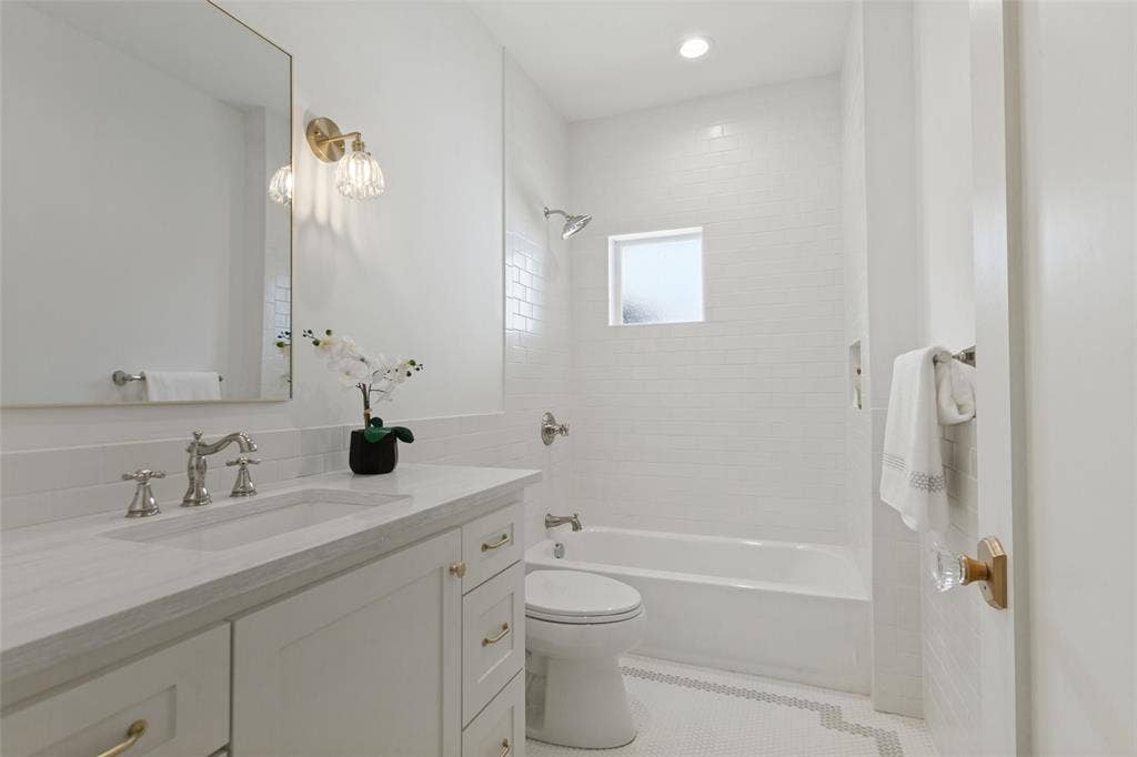 304 S Weatherred Drive, Richardson, TX 75080 Bathroom featuring white cabinetry, stone-finish countertop, polished metal fixtures, white subway tile shower surround, and mosaic tile flooring