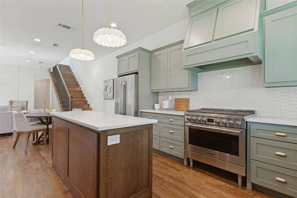 304 S Weatherred Drive, Richardson, TX 75080 Kitchen featuring sage green cabinetry, a wood-finish island, a stainless steel gas range with a custom hood, and a white picket-style tile backsplash