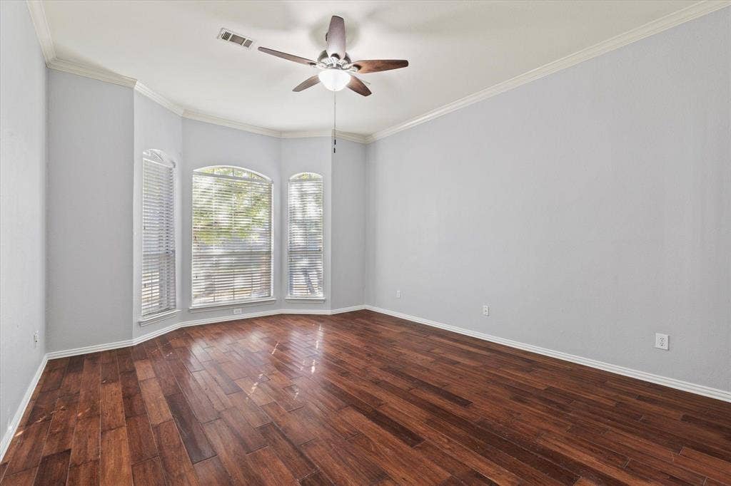 892 Brentwood Drive, Coppell, TX 75019 Room featuring dark wood-finish flooring, a multi-window bay configuration with arched top panes, and a central ceiling fan with integrated lighting