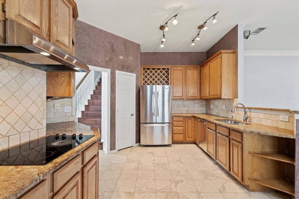 892 Brentwood Drive, Coppell, TX 75019 Kitchen featuring stained-wood cabinetry, stone countertops, diamond-pattern tile backsplash, stainless steel appliances, and built-in wine storage