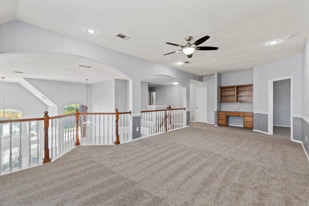 892 Brentwood Drive, Coppell, TX 75019 Upstair Living Area. Open-concept interior featuring arched architectural detailing, a wooden handrail with balusters, recessed lighting, a ceiling fan, and built-in wooden cabinetry