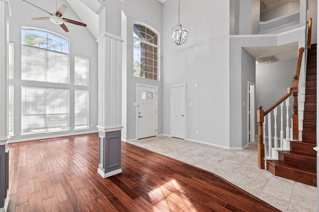 892 Brentwood Drive, Coppell, TX 75019 Double-height ceilings featuring large arched windows, wood-finish flooring, tile flooring, and a staircase with a wooden handrail and balusters