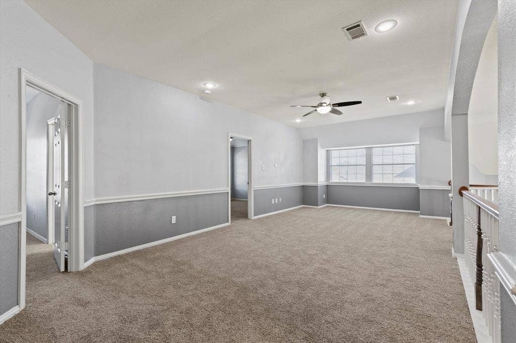 892 Brentwood Drive, Coppell, TX 75019 Upstairs Living Area. Spacious room featuring high ceilings, neutral carpeting, two-toned wall paint, recessed lighting, and a ceiling fan