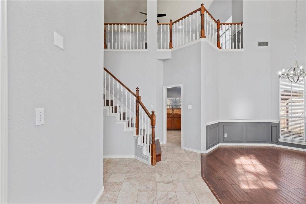892 Brentwood Drive, Coppell, TX 75019 Double-height foyer featuring a staircase with wooden handrails and balusters, tile flooring, wood-finish flooring, and wainscoting