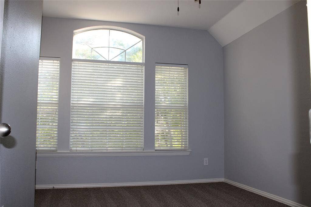 892 Brentwood Drive, Coppell, TX 75019 Room featuring a vaulted ceiling, arched window, wall-to-wall carpeting, and horizontal blinds