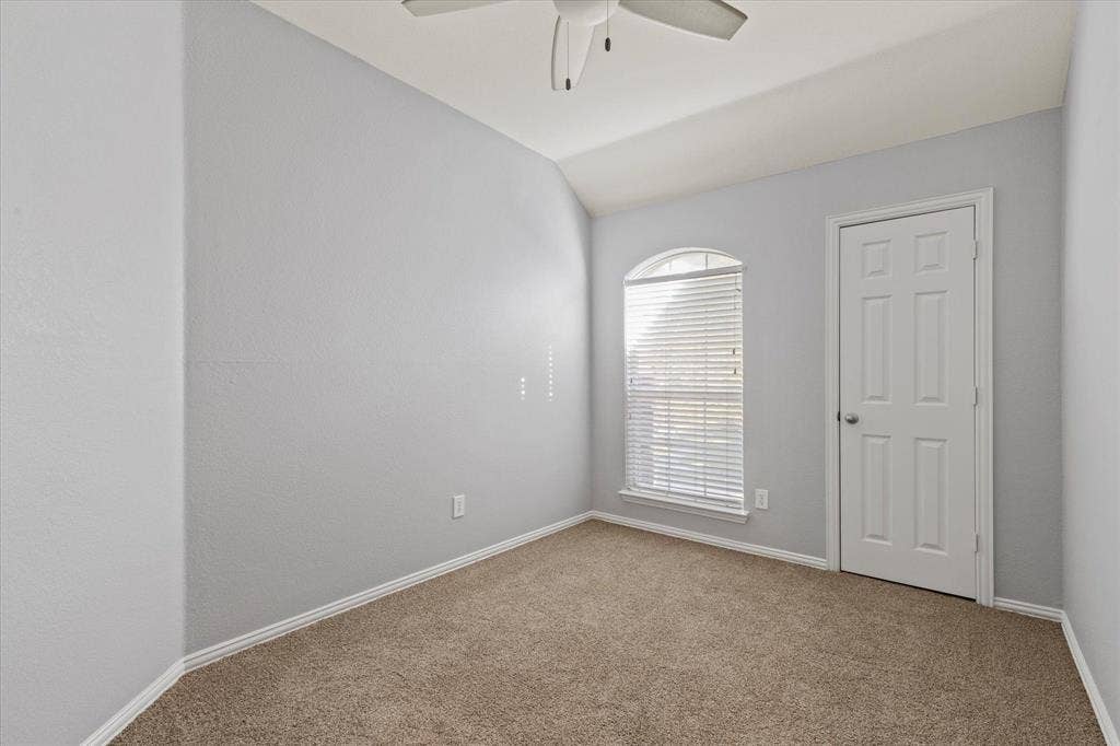 892 Brentwood Drive, Coppell, TX 75019 Vaulted ceilings, neutral wall color, arched window with horizontal blinds, neutral carpeting, and a ceiling-mounted fan