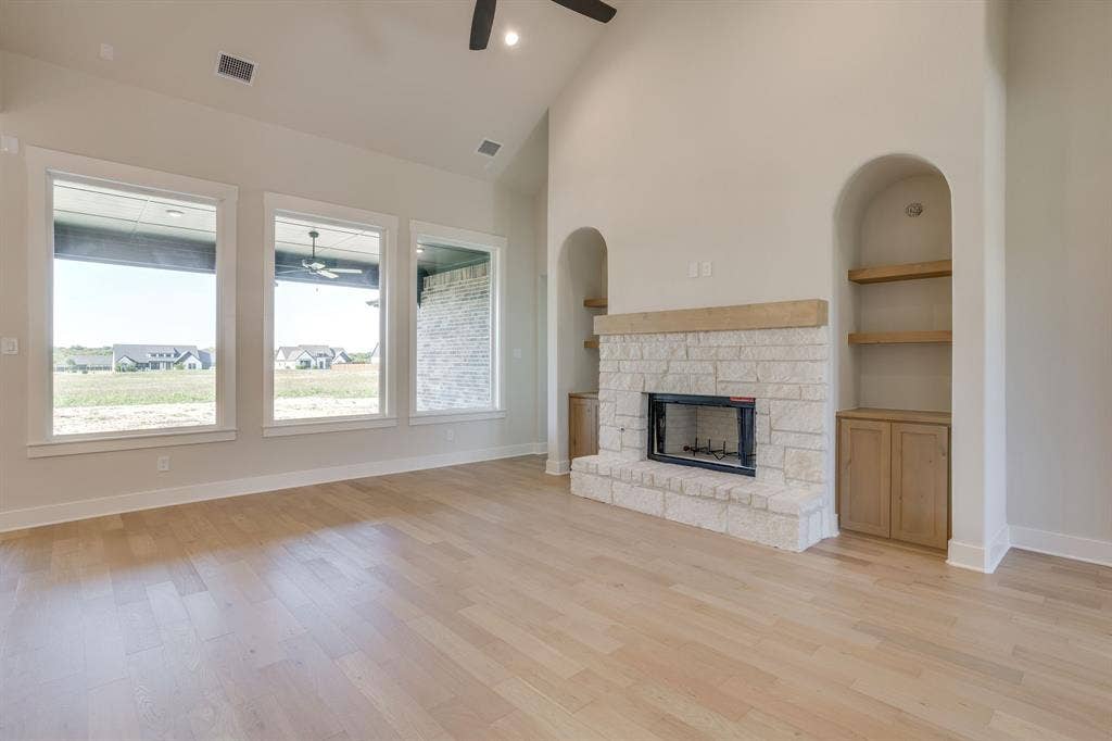 501 Olson Road, Waxahachie, TX 75167 Vaulted ceiling, stone-surround fireplace with a timber mantel, built-in cabinetry, and wood-finish flooring