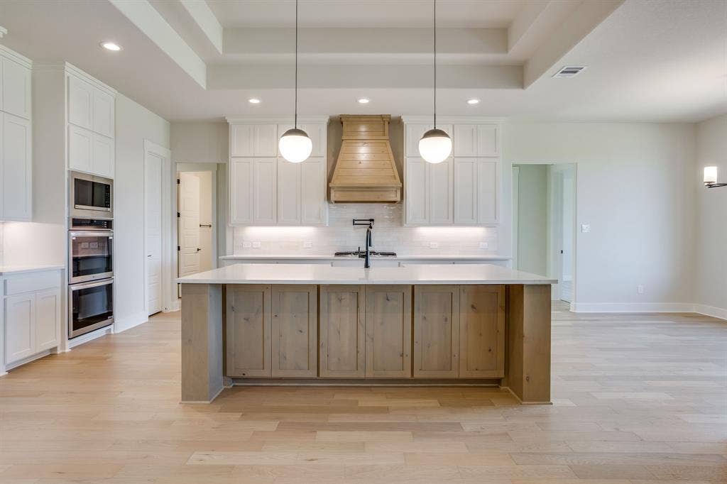 501 Olson Road, Waxahachie, TX 75167 Kitchen featuring white shaker cabinetry, wood-finish center island, quartz countertops, custom wood range hood, and double wall ovens