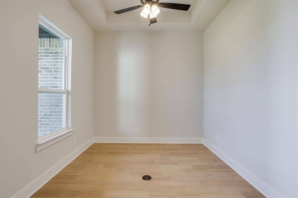 501 Olson Road, Waxahachie, TX 75167 Tray ceiling featuring a central ceiling fan with multi-light fixture, wood-finish flooring, and a single-pane window