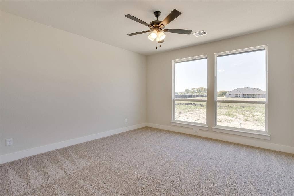 501 Olson Road, Waxahachie, TX 75167 Neutral-toned interior featuring wall-to-wall carpeting, dual windows, and a ceiling-mounted light fixture with a multi-blade fan