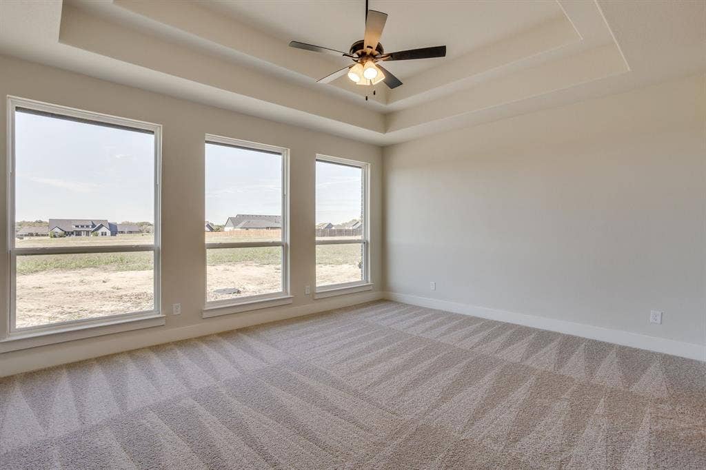 501 Olson Road, Waxahachie, TX 75167 Tray ceiling with a central multi-blade ceiling fan and three large picture windows providing natural light