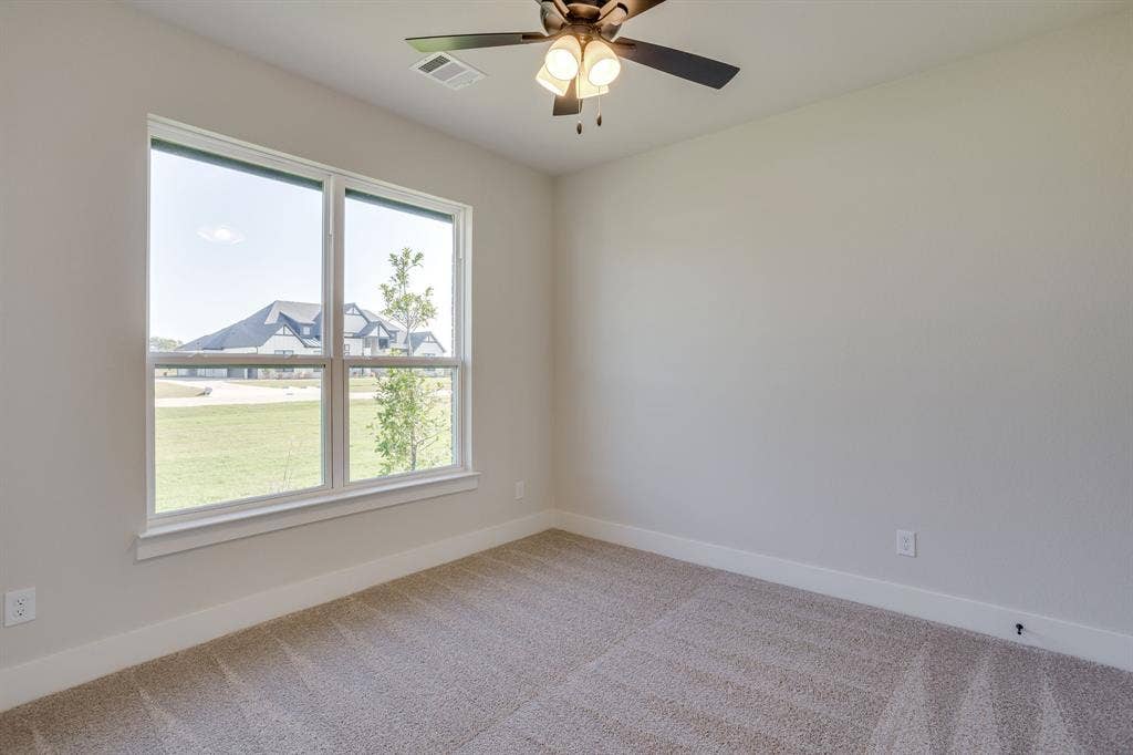 501 Olson Road, Waxahachie, TX 75167 Neutral-toned interior featuring plush carpeting, a large window with exterior exposure, and a ceiling-mounted fan with integrated lighting
