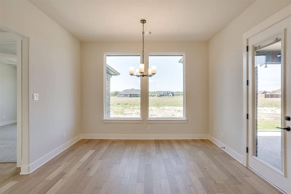 501 Olson Road, Waxahachie, TX 75167 Light-filled room featuring wood-finish flooring, dual picture windows, an overhead multi-light chandelier, and a glass-paneled exterior door