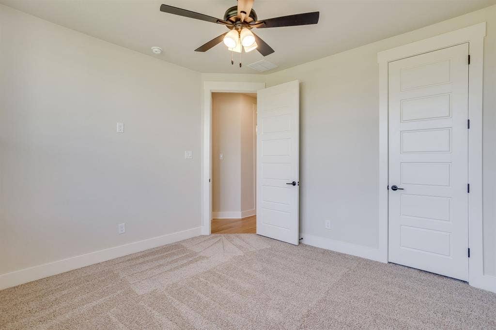 501 Olson Road, Waxahachie, TX 75167 Neutral-toned carpeted room featuring a ceiling fan with integrated lighting and five-panel interior doors with matte black hardware