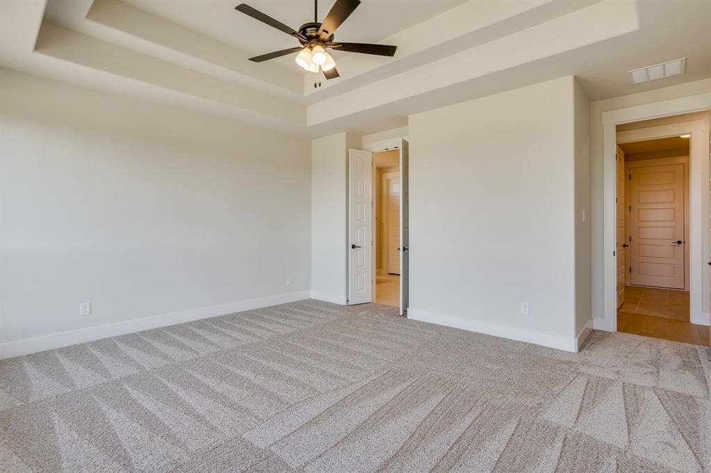 501 Olson Road, Waxahachie, TX 75167 Tray ceiling with a central multi-blade ceiling fan and integrated lighting, neutral wall-to-wall carpeting, and multi-panel interior doors