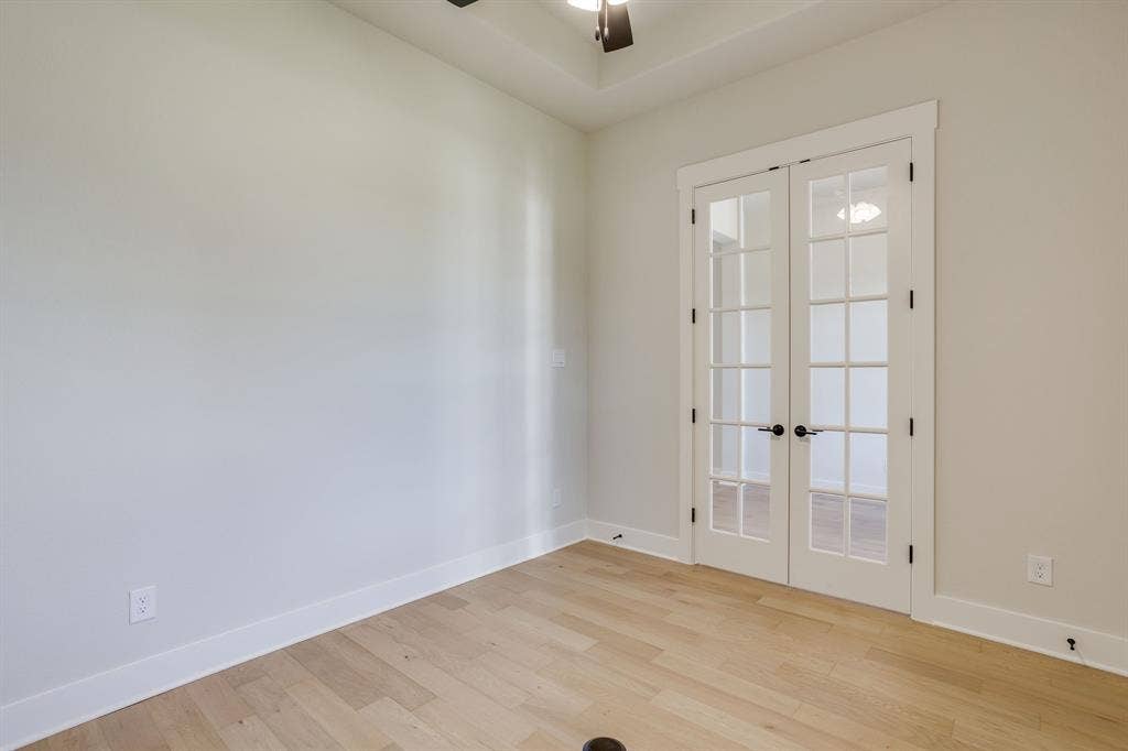 501 Olson Road, Waxahachie, TX 75167 Tray ceiling featuring a central ceiling fan, light-toned wood-finish flooring, and white double French doors with glass panes and dark hardware