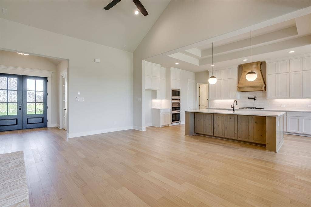 501 Olson Road, Waxahachie, TX 75167 Vaulted ceilings with recessed lighting, wood-finish flooring, double-entry doors, kitchen island with wood-finish cabinetry, and custom range hood