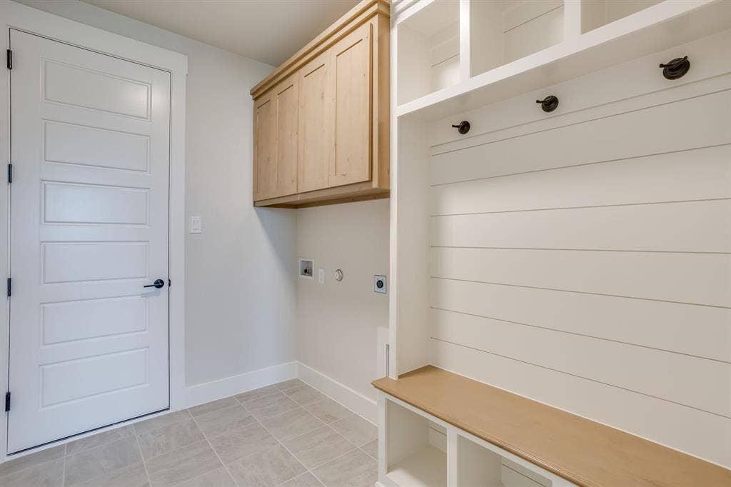 501 Olson Road, Waxahachie, TX 75167 Built-in mudroom bench with shelving, light wood-finish cabinetry, white horizontal shiplap wall detailing, tile flooring, and a five-panel interior door with matte black hardware