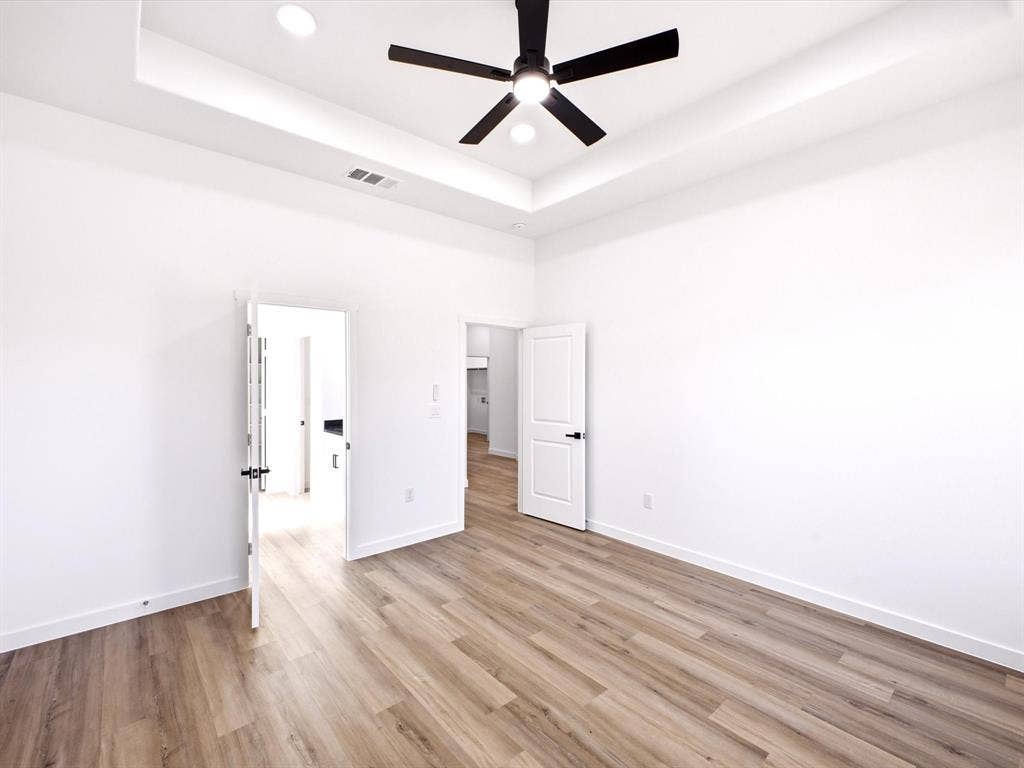 5365 Rabbit Trail, Kemp, TX 75143 Tray ceiling featuring recessed lighting, matte black ceiling fan, wood-finish flooring, and solid-core doors with matte black hardware